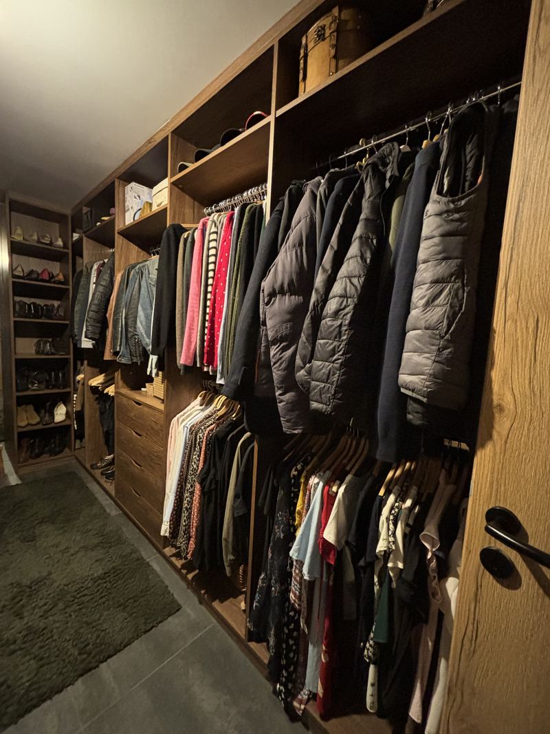 Dressing ouvert en décor chêne foncé : penderies garnies, étagères, tiroirs et rangement à chaussures en enfilade